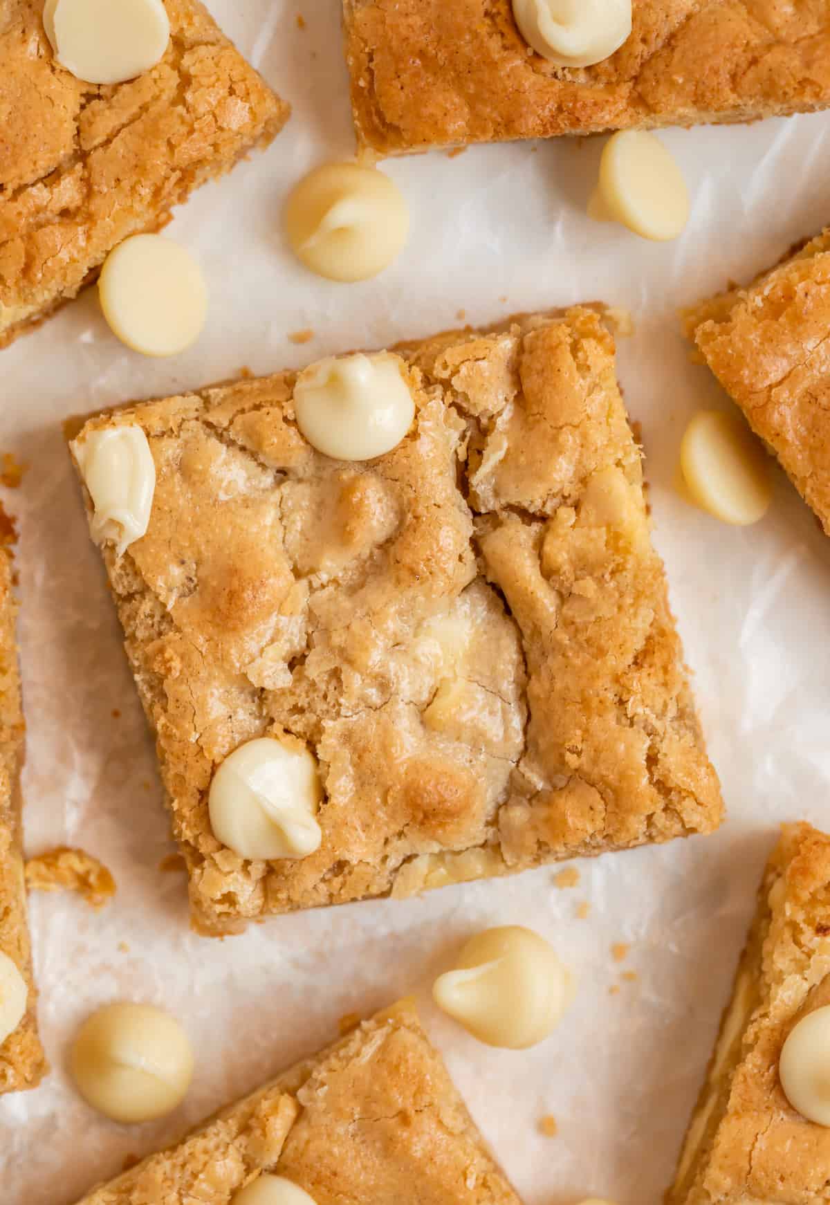 Gluten free blondies with white chocolate chips arranged on parchment.