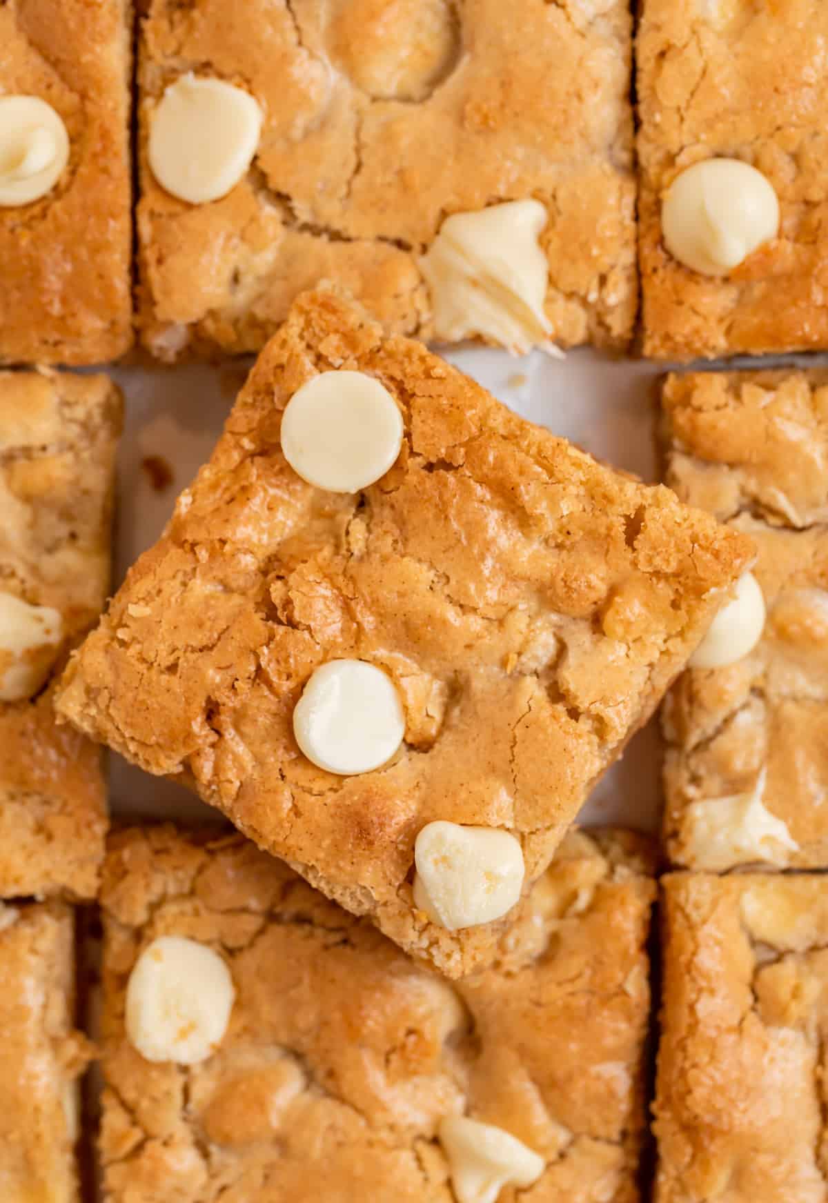 Gluten free almond flour blondies with white chocolate chips lined up with top slice tilted slightly.