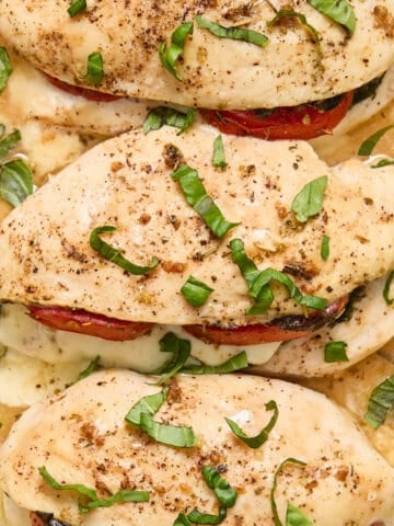 Close up view of stuffed chicken breasts topped with freshly chopped basil.