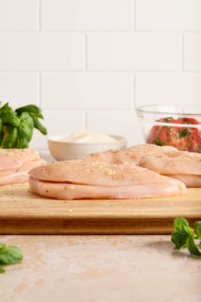 Sliced chicken breast on cutting board ready to be stuffed with cheese.