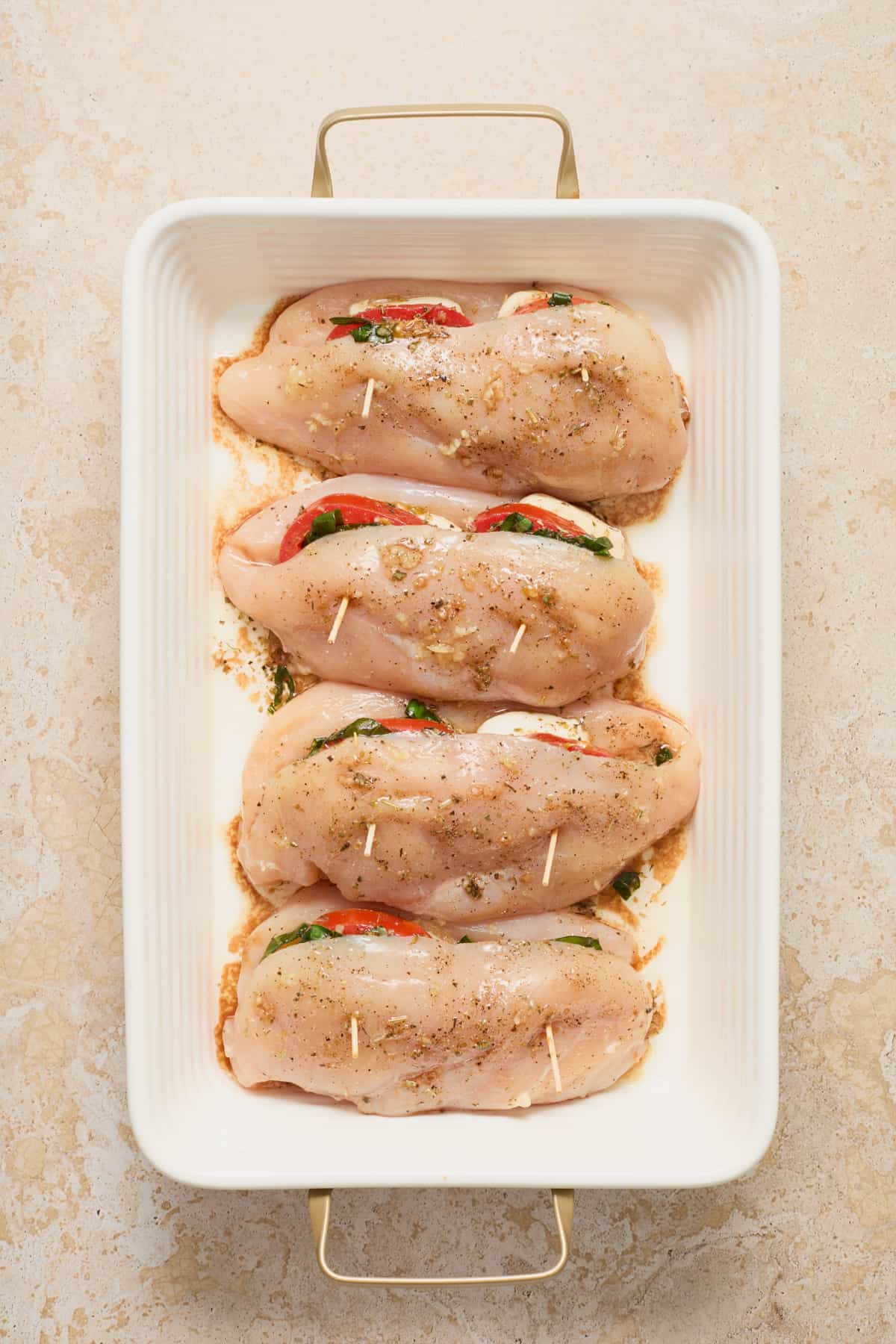 Baking dish with mozzarella, tomato and basil stuffed chicken breasts before baking.