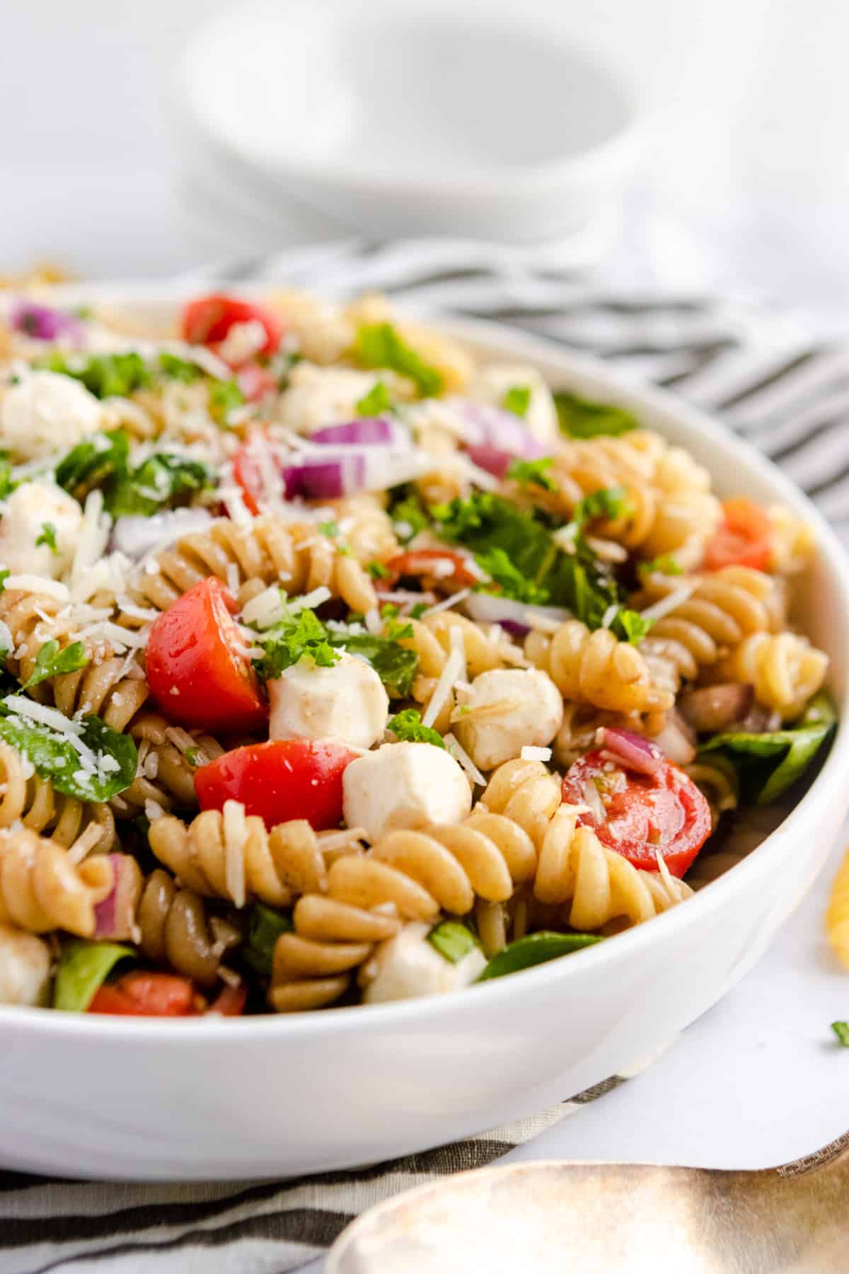 Tomato Basil Rotini Pasta Salad in white bowl.