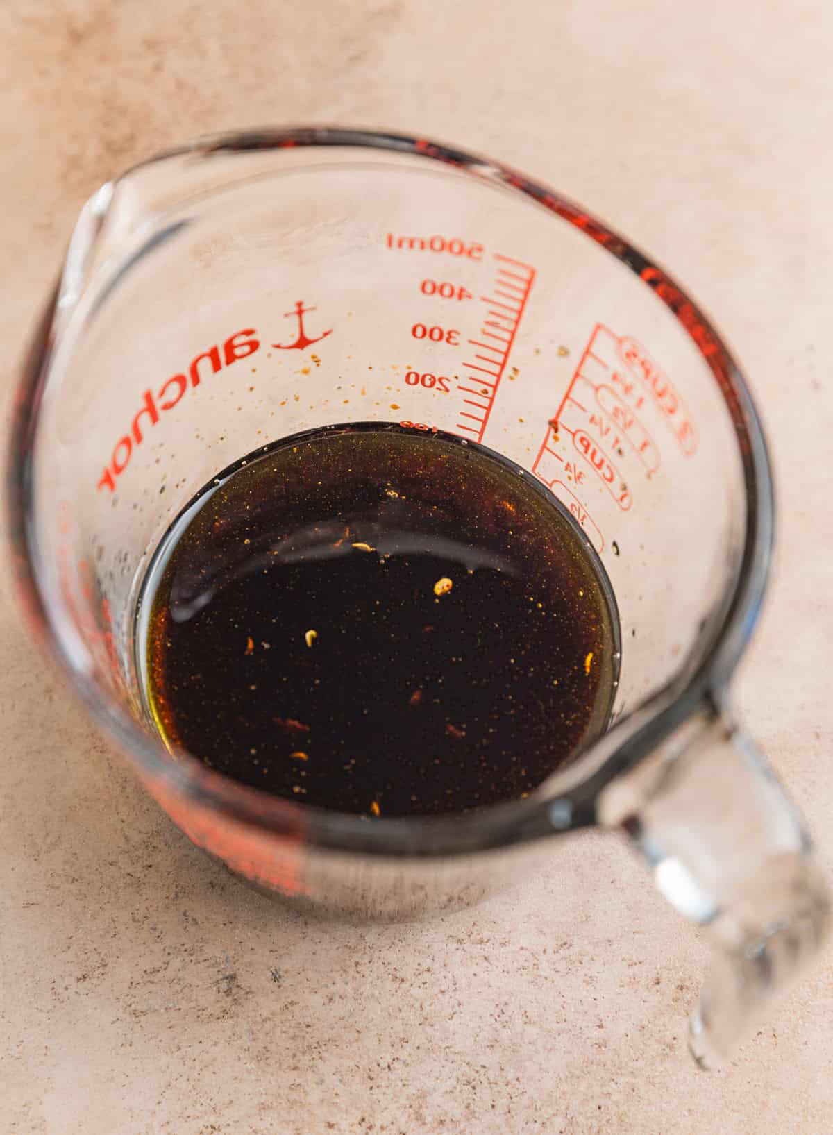 Olive oil, balsamic vinegar, garlic, salt and pepper mixed in measuring cup.