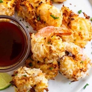 Coconut shrimp on white plate with sauce.