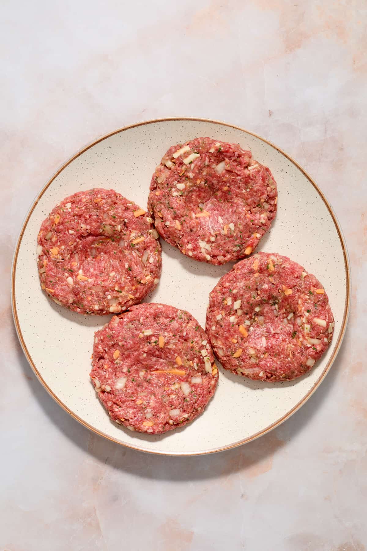 Hamburger patties on plate prepped with dimple in center.