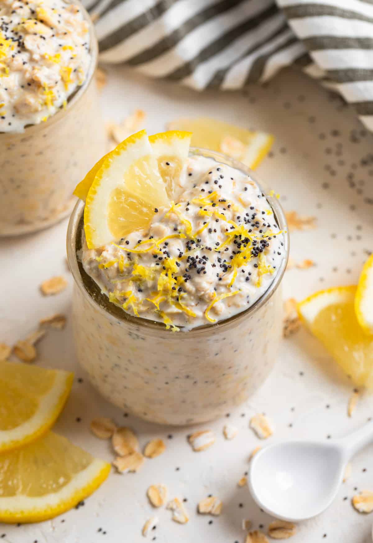 Lemon poppy seed overnight oats in glass jar with lemon zest and poppy seeds on top.