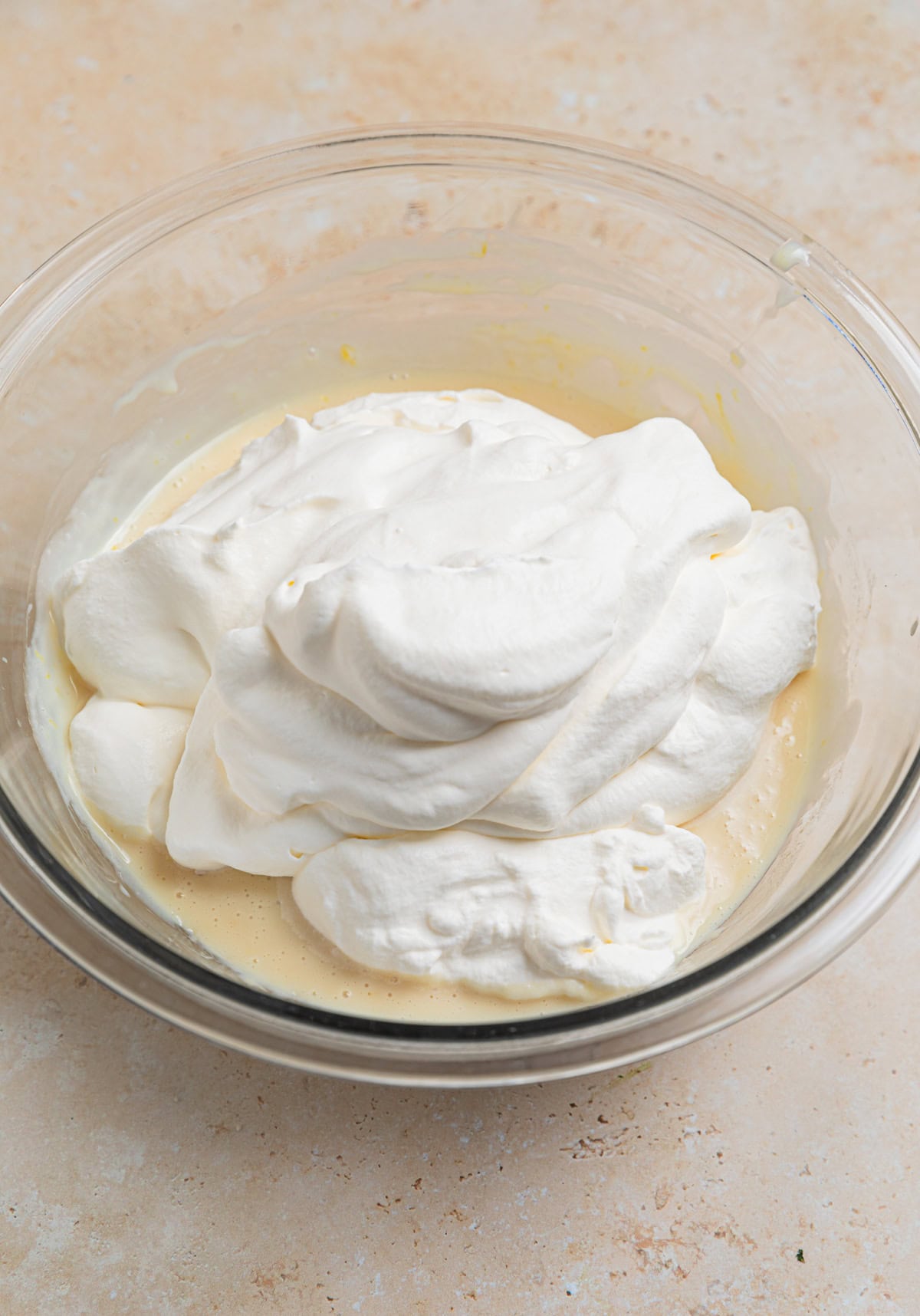 Whipped cream and condensed milk mixture in glass mixing bowl.