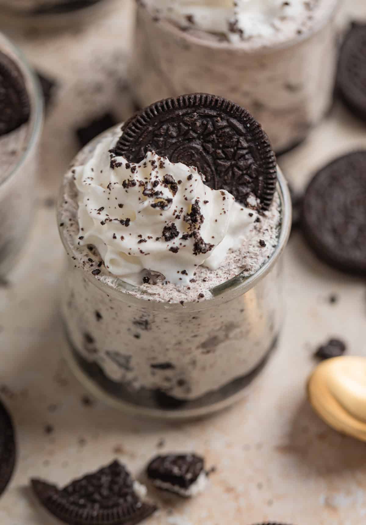 No bake Oreo cheesecake cup topped with whipped cream and crushed Oreo cookies.