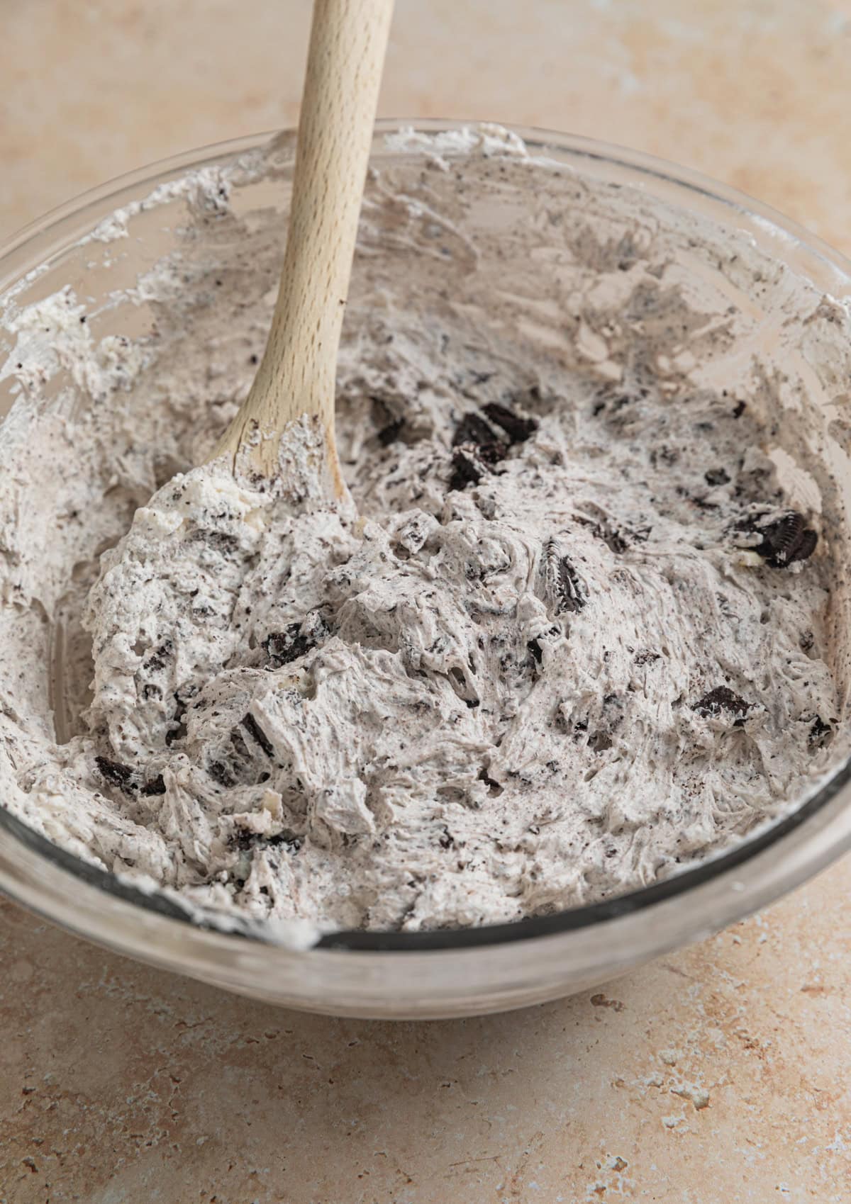 No bake Oreo cheesecake filling in bowl with spoon.