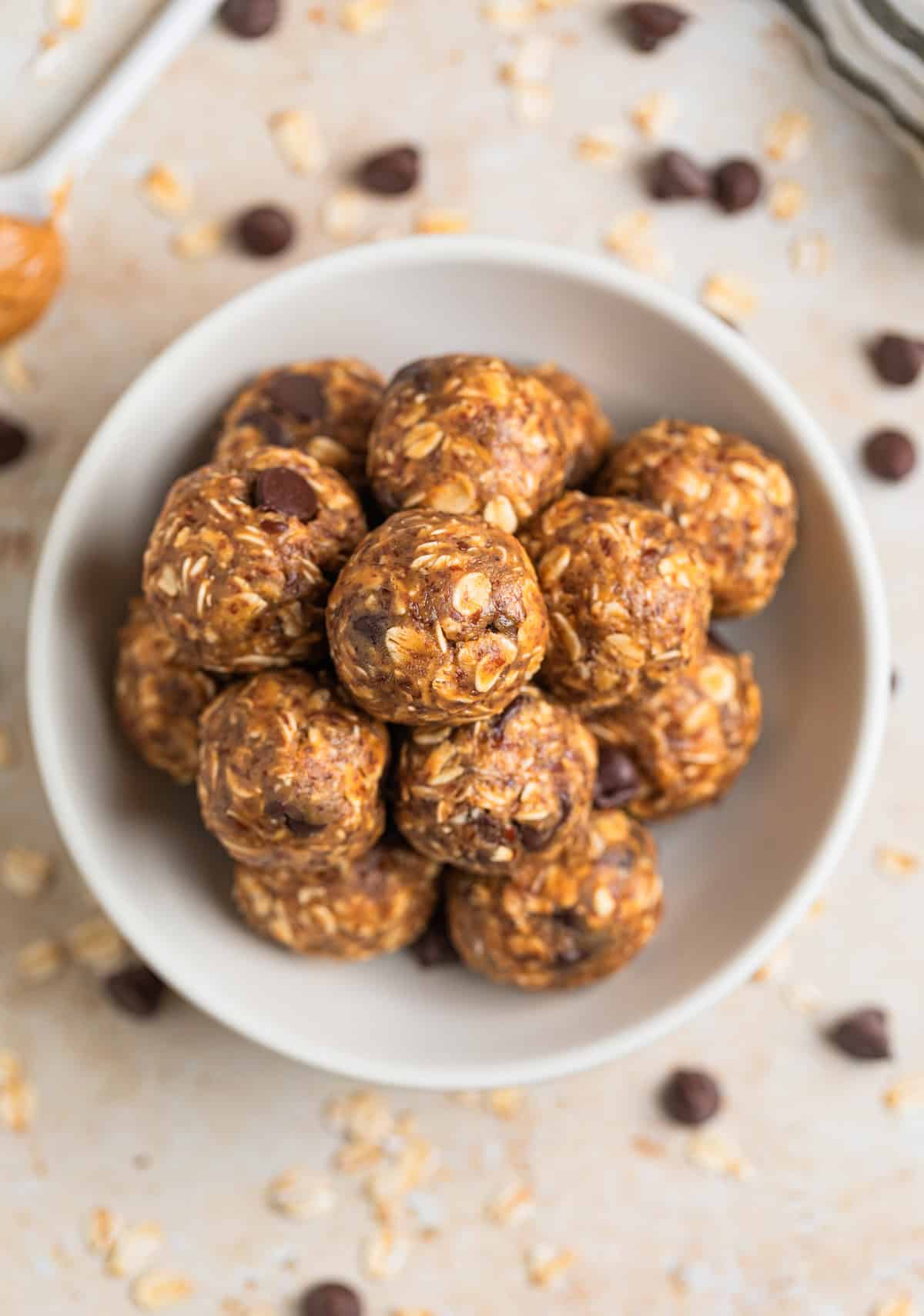Peanut butter oat bites with spoonful of peanut butter beside the dish holding the bites.
