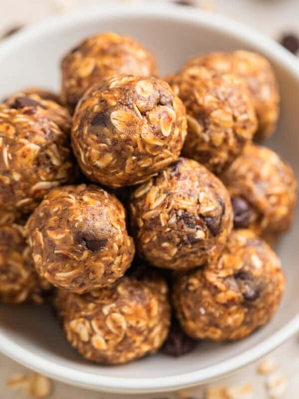 White ceramic bowl with peanut butter oatmeal energy bites with chocolate chips and oats scattered around the bowl.