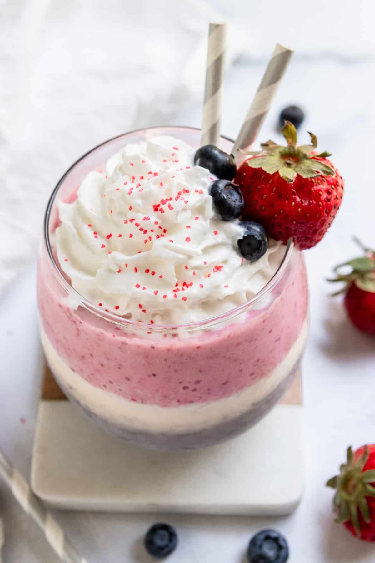 Red white and blue milkshake with whipped cream and fruit.