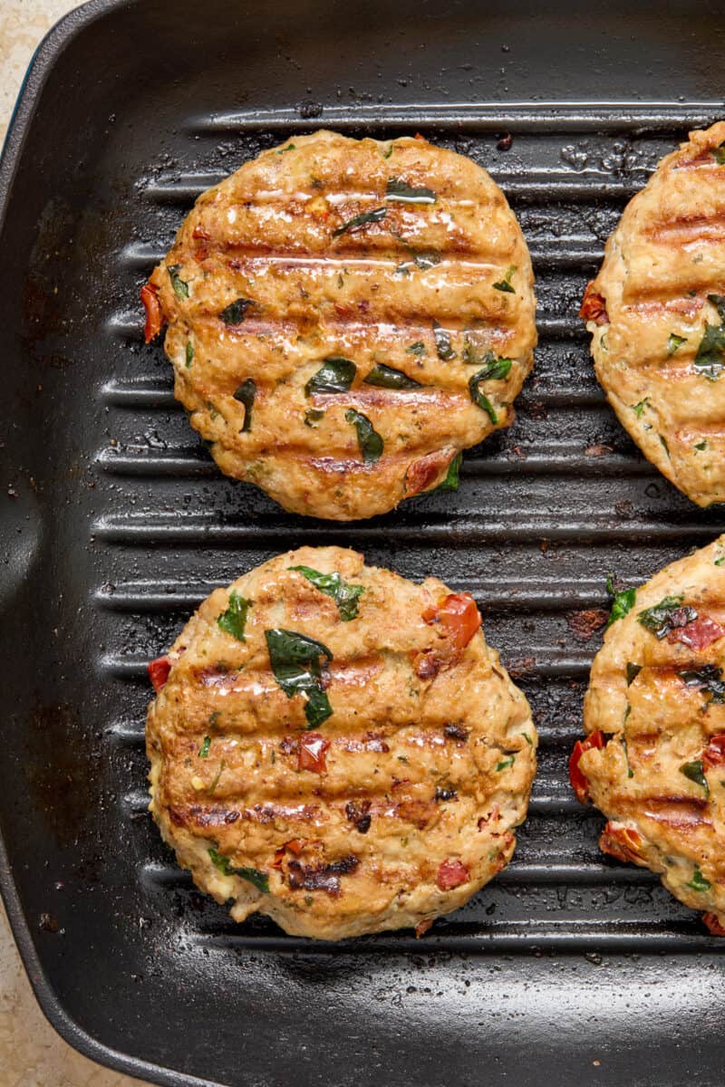 Cooked turkey burgers in grill skillet.