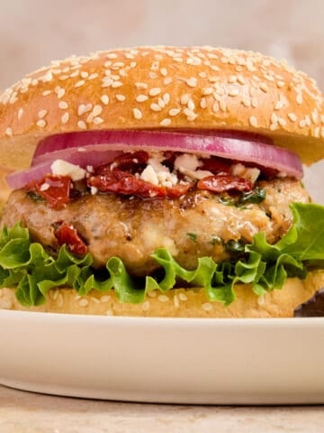 Turkey burger with spinach and feta on bun with lettuce, onion and other ingredients.