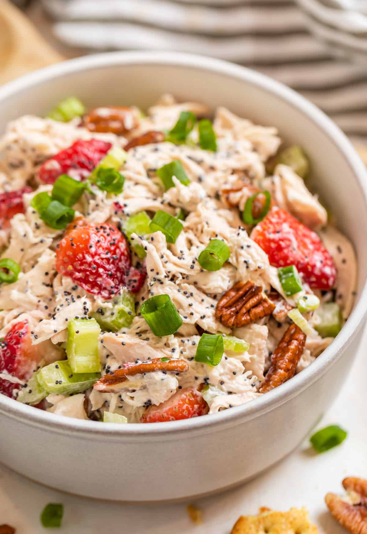 Strawberry chicken salad with pecans, poppy seeds and green onion in ceramic bowl.