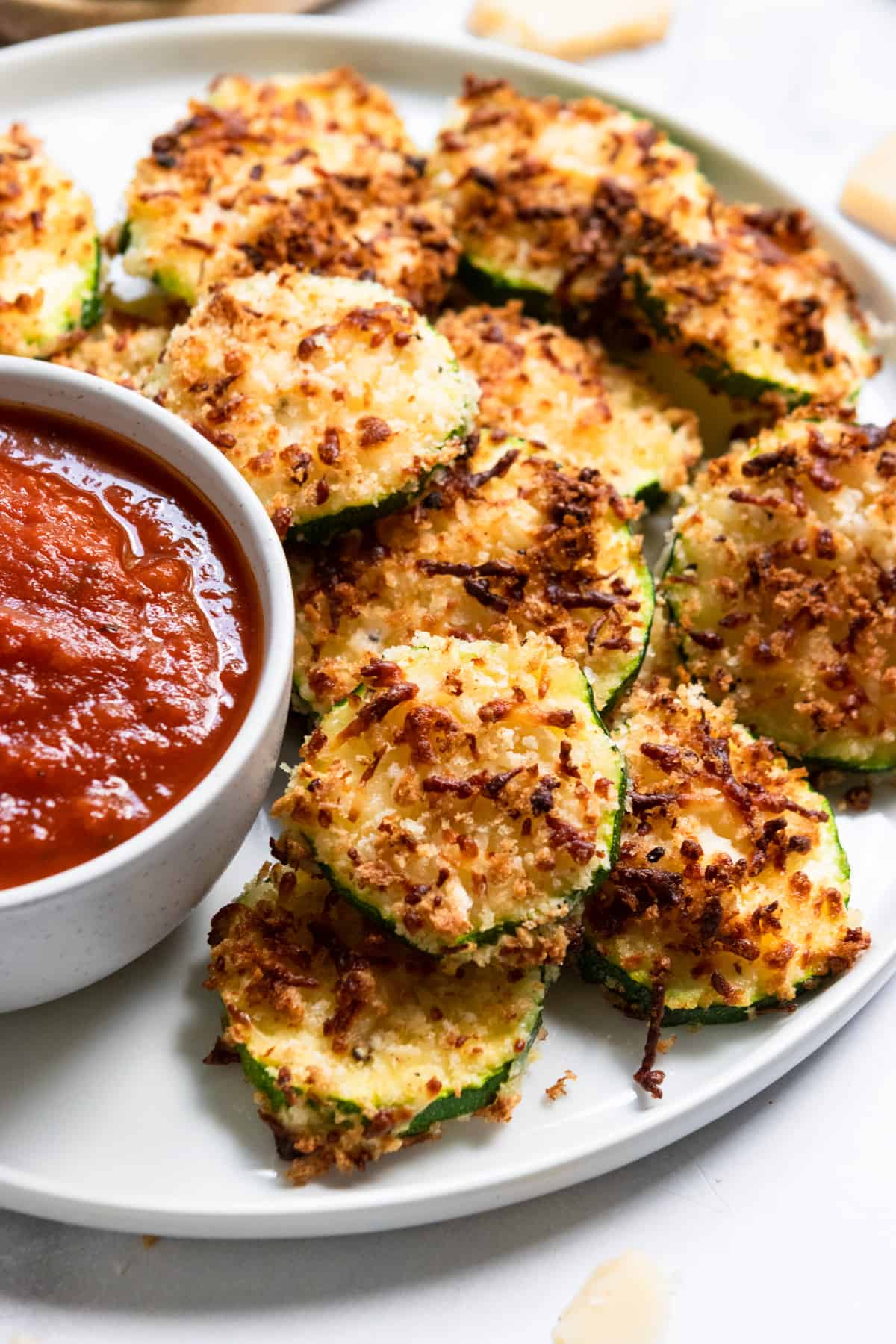 Air fried zucchini on white plate with marinara.