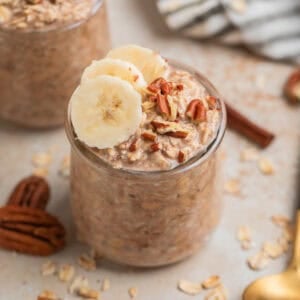 Glass jar with overnight oatmeal topped with bananas and nuts.