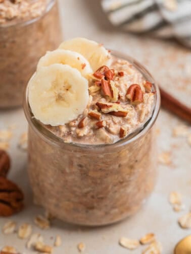 Glass jar with overnight oatmeal topped with bananas and nuts.
