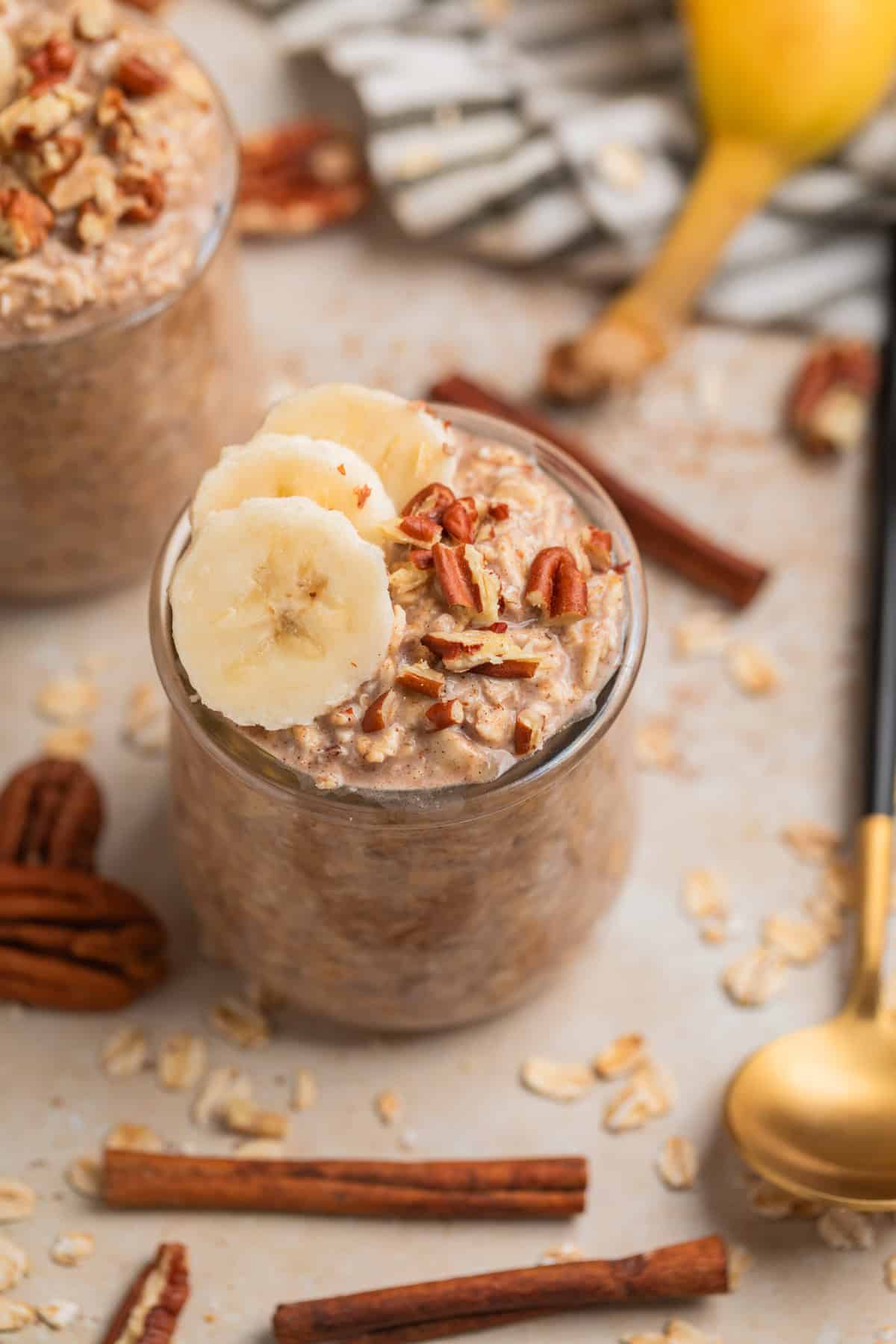 Banana bread overnight oats in jar topped with sliced bananas and chopped pecans.