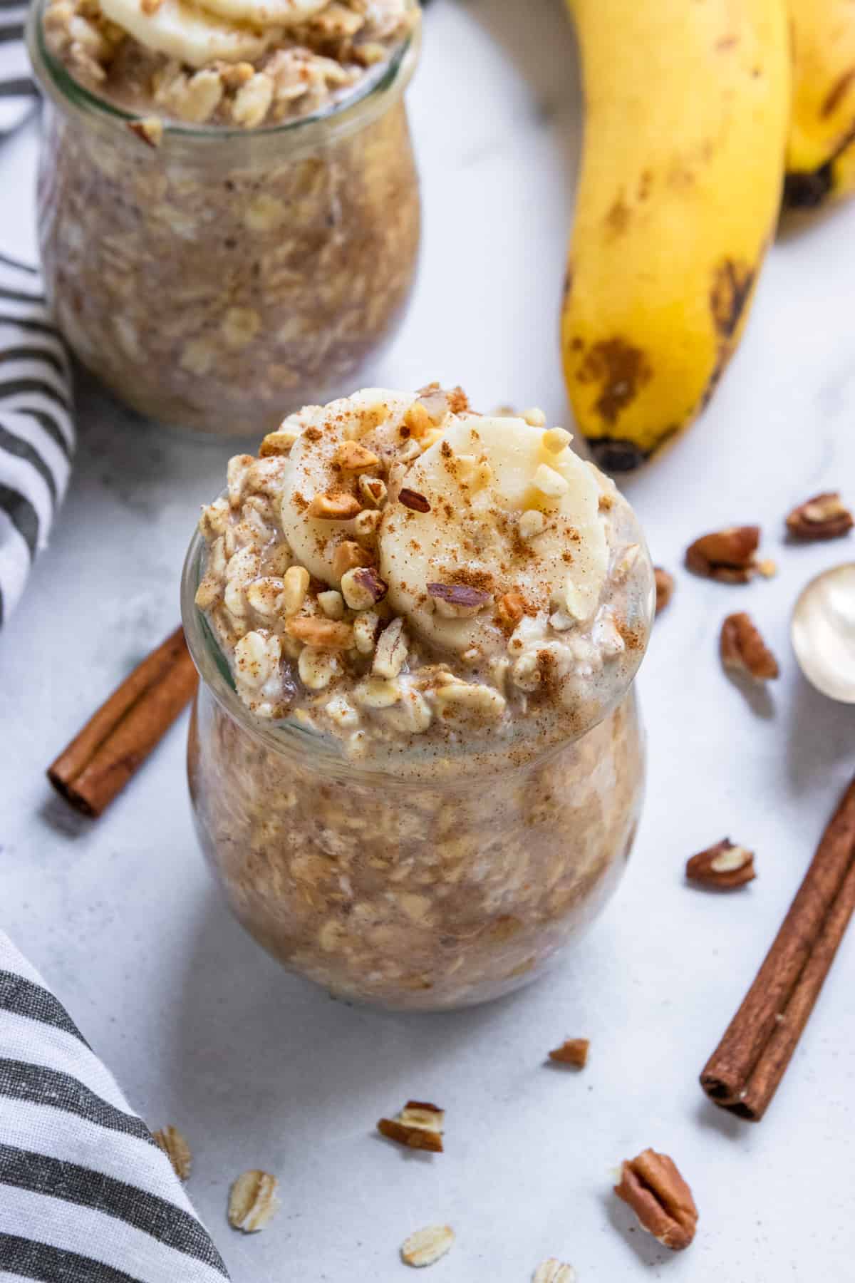 Banana Overnight Oats in jar with pecans and banana slices.