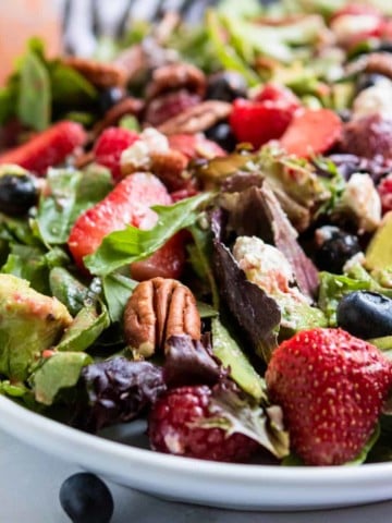 Berries and pecans over green salad.