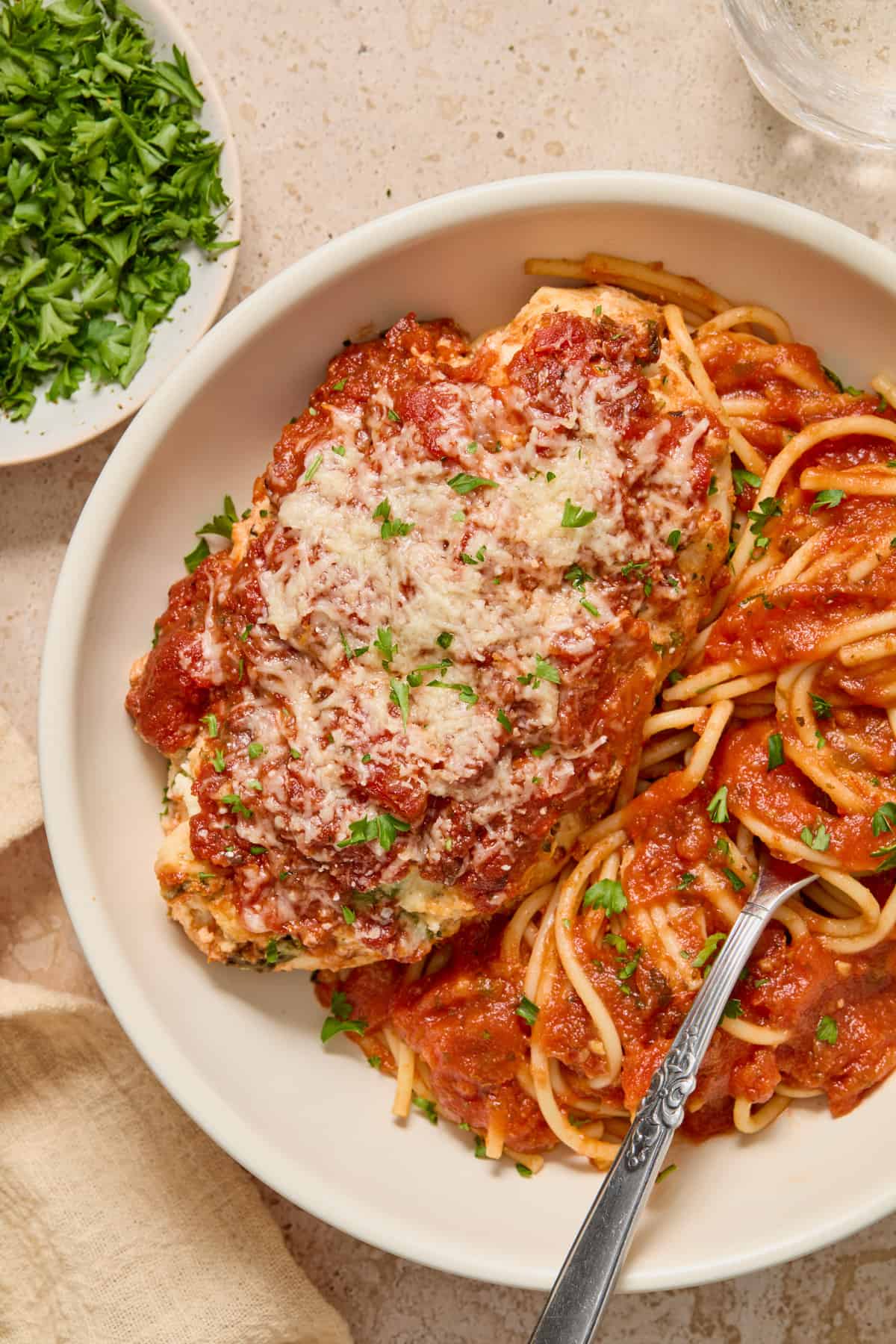 Baked chicken in bowl of spaghetti with fork.