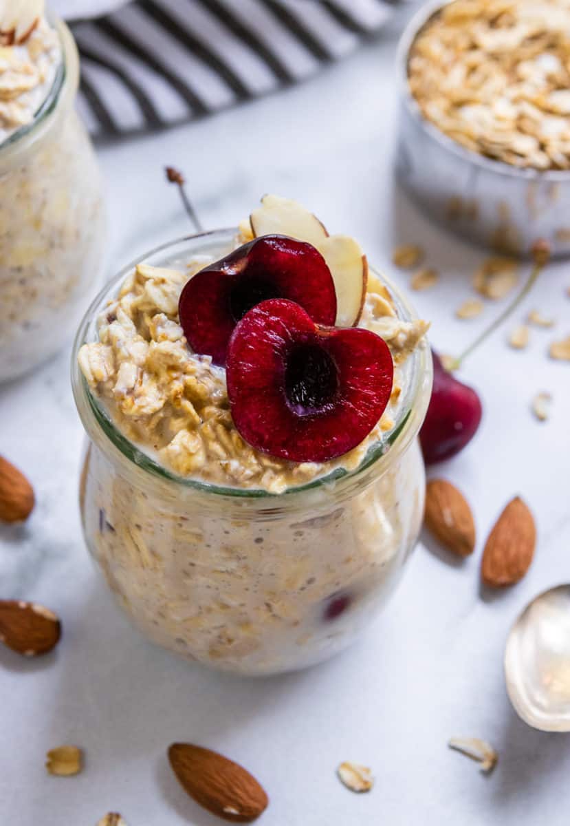Vegan overnight oats in jars with cherries on top.
