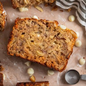 Banana bread slice with white chocolate chips and other slices surrounding.
