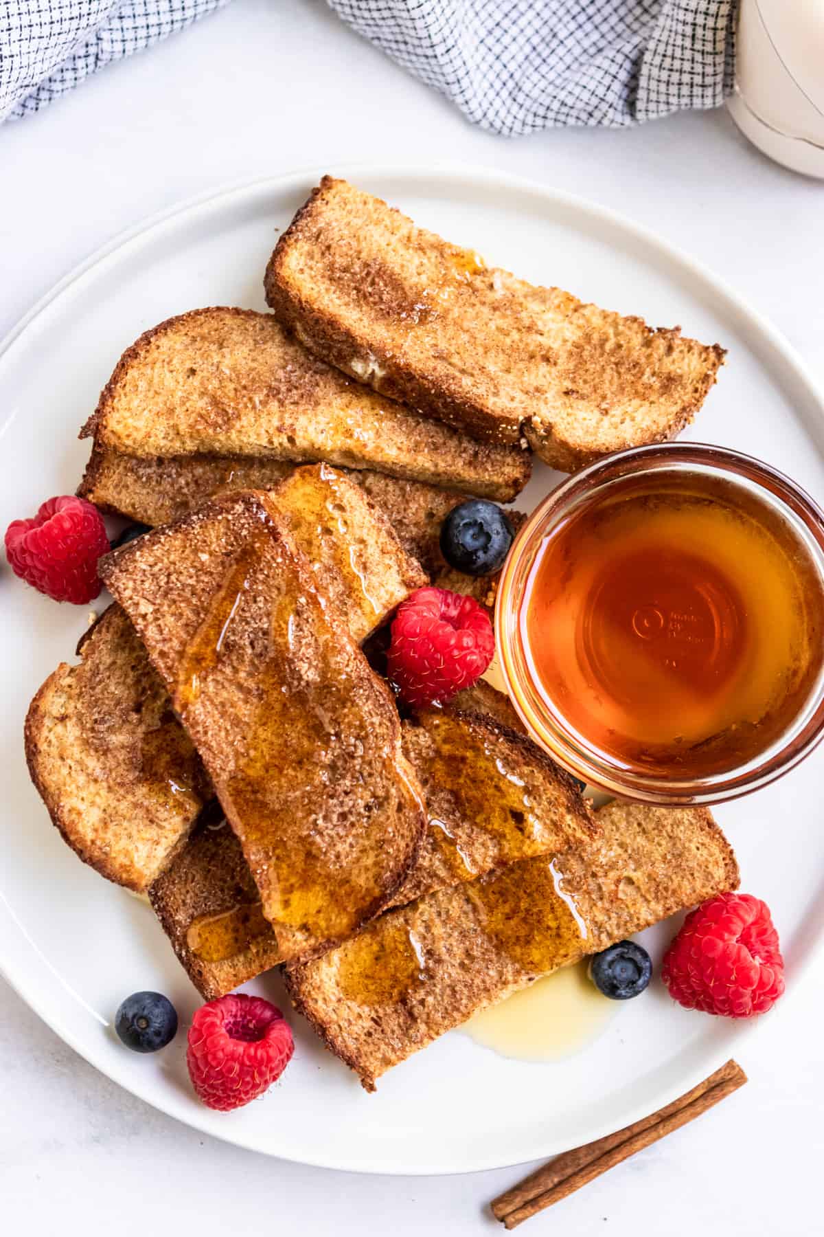 White plate with whole grain air fryer french toast sticks and maple syrup.