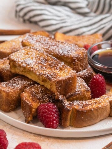 Plate with air fryer French toast sticks dusted with powdered sugar.