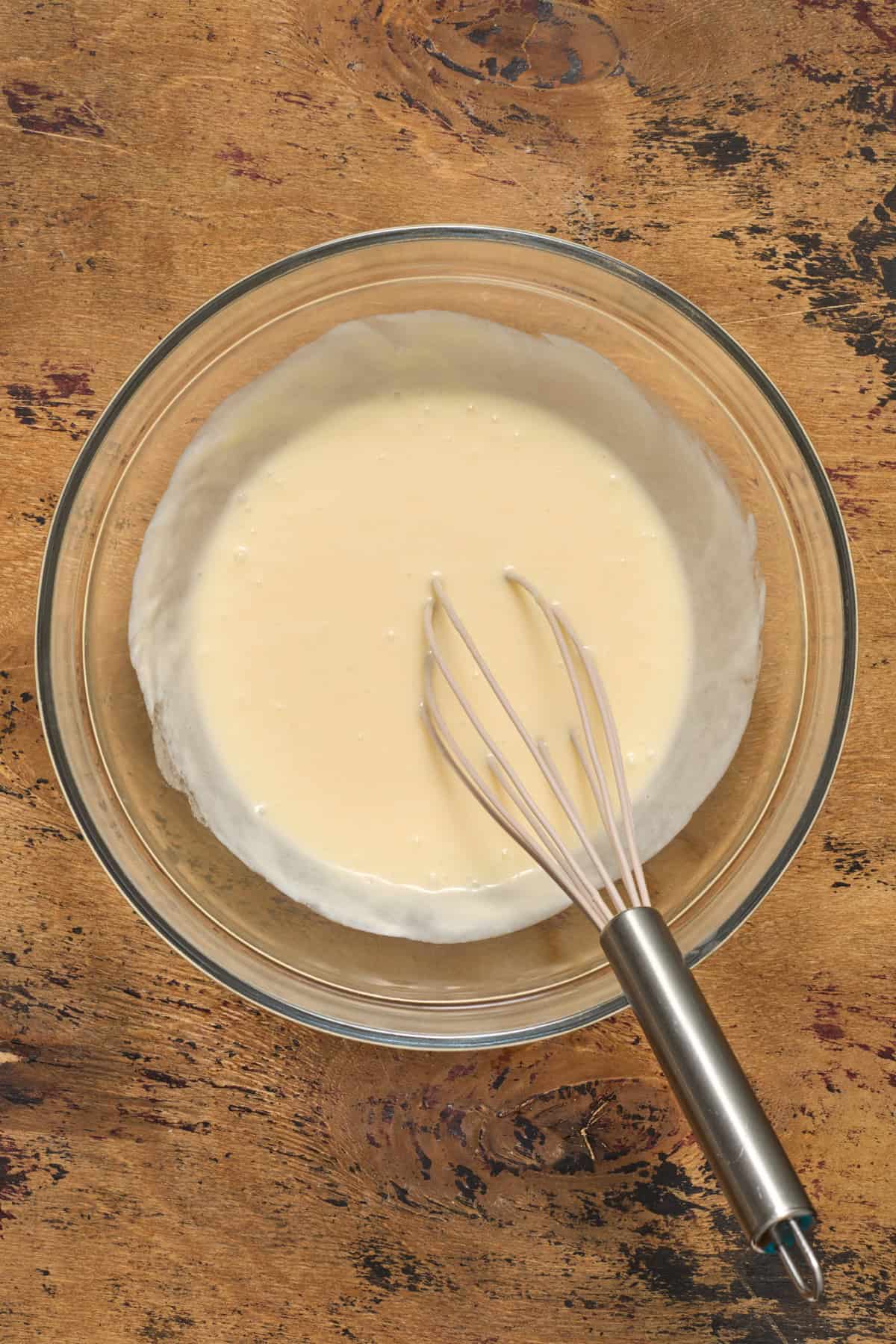 Egg, honey, sour cream and butter whisked in glass bowl.