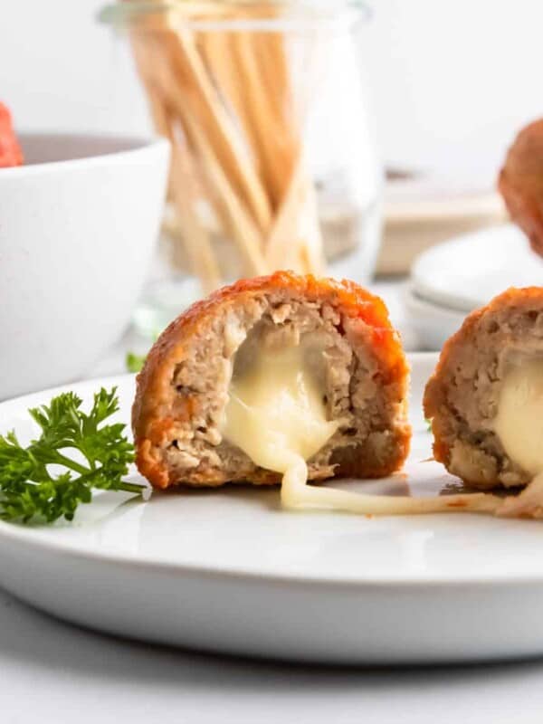 Mozzarella stuffed turkey meatballs on plate with cheese stretching.