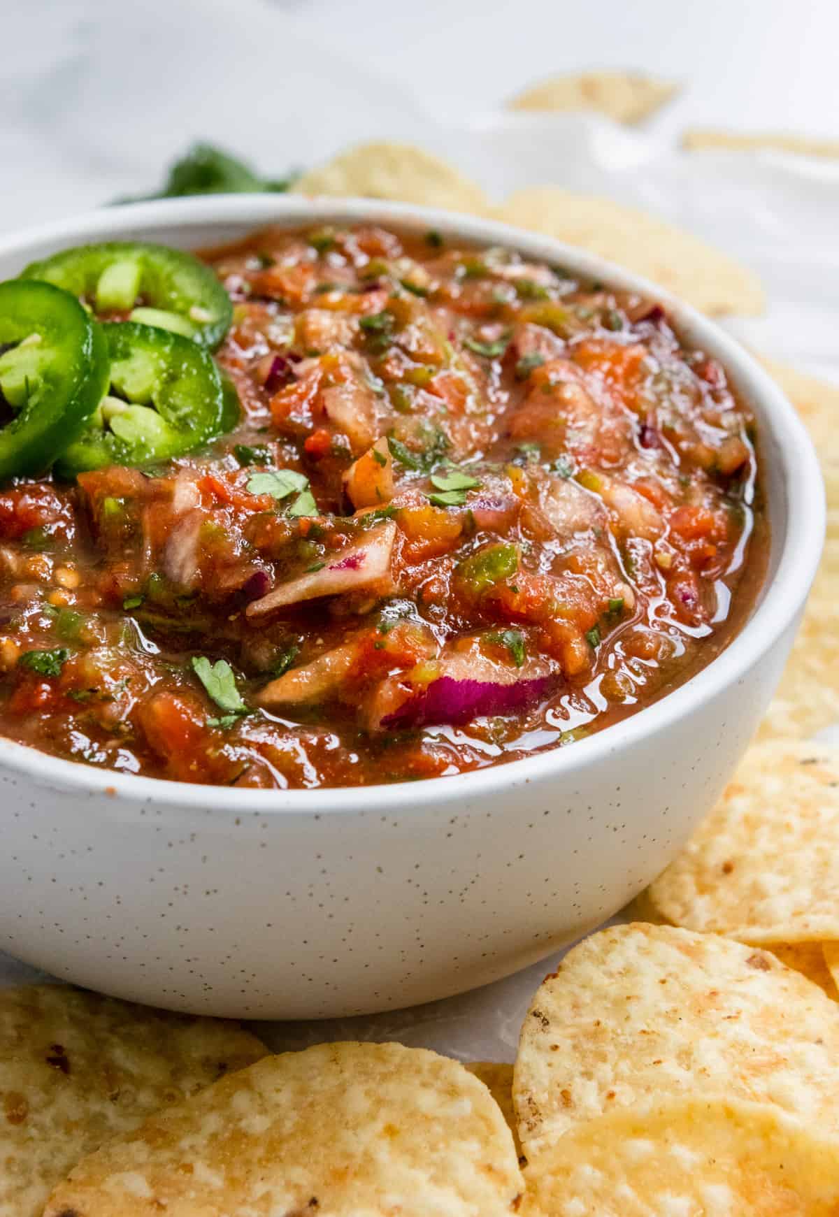 Roasted tomato salsa in bowl with jalapeños.