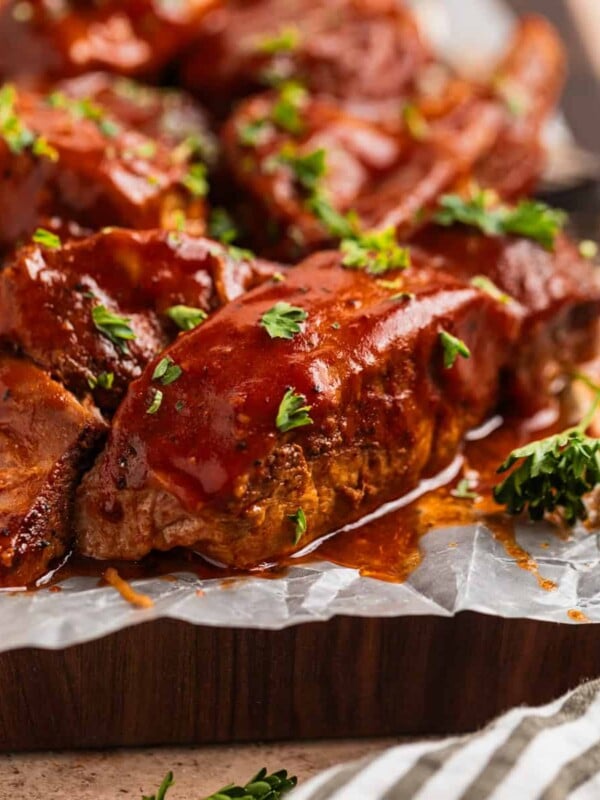 BBQ boneless pork ribs on wax paper lined cutting board topped with chopped fresh parsley.