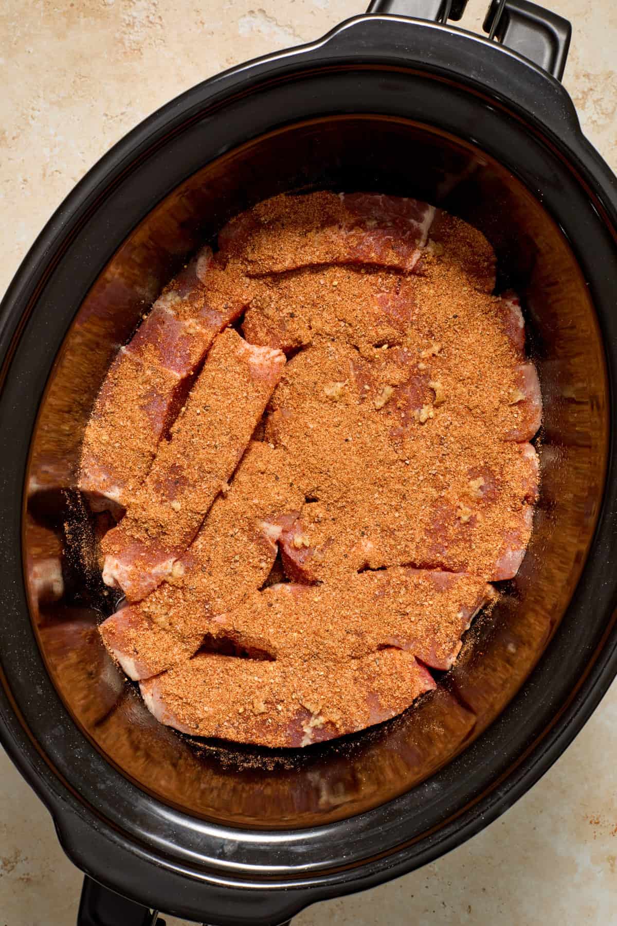 Country style ribs in crock pot with spice rub over top.