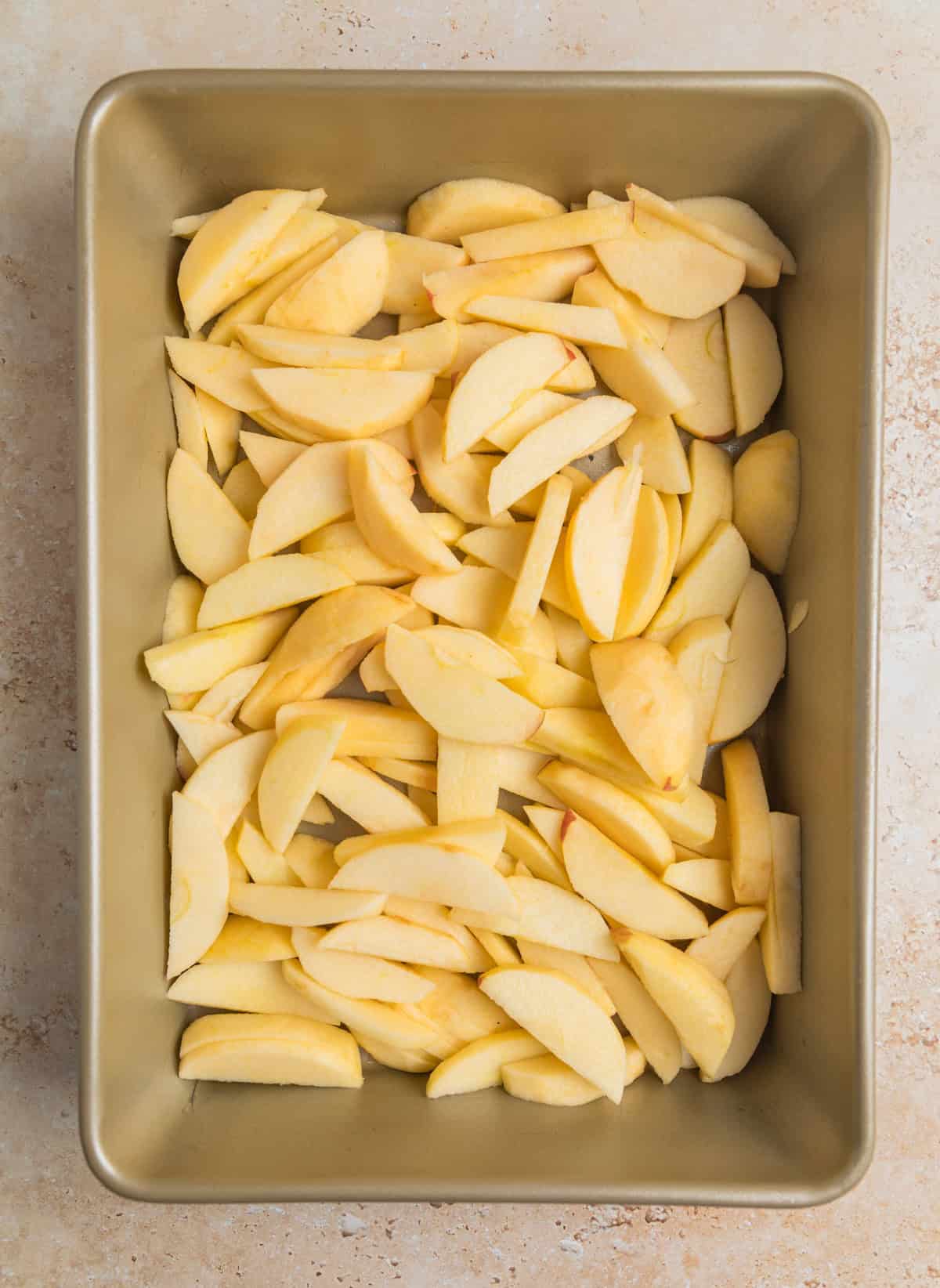 Peeled, sliced apples in baking pan.