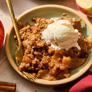 Apple spice cake with gooey apples on plate with vanilla ice cream.