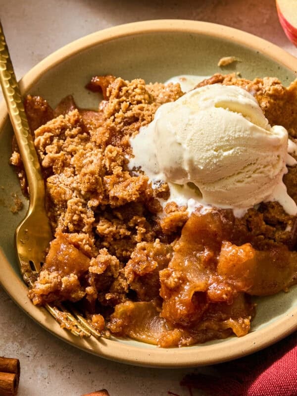 Apple spice cake with gooey apples on plate with vanilla ice cream.