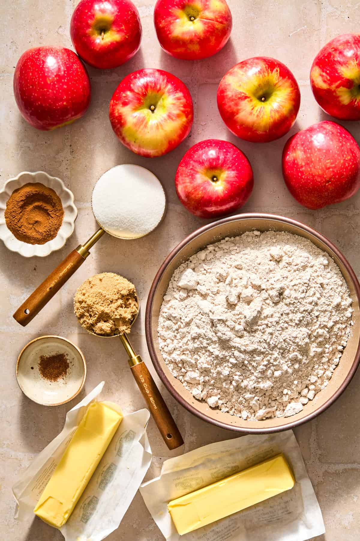 Spice cake mix, apples, cinnamon, butter and other ingredients on surface.