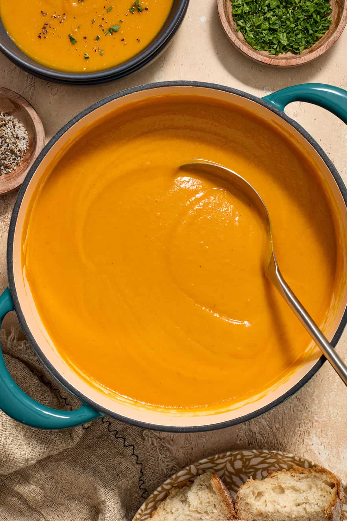 Pot with smooth and creamy roasted sweet potato carrot soup with ladle.