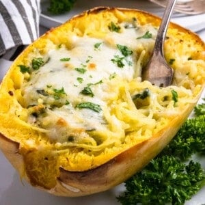 Creamy pesto spaghetti squash half with fork.