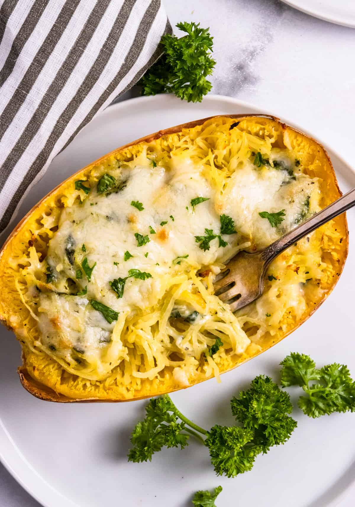 Pesto stuffed spaghetti squash with fork in it.