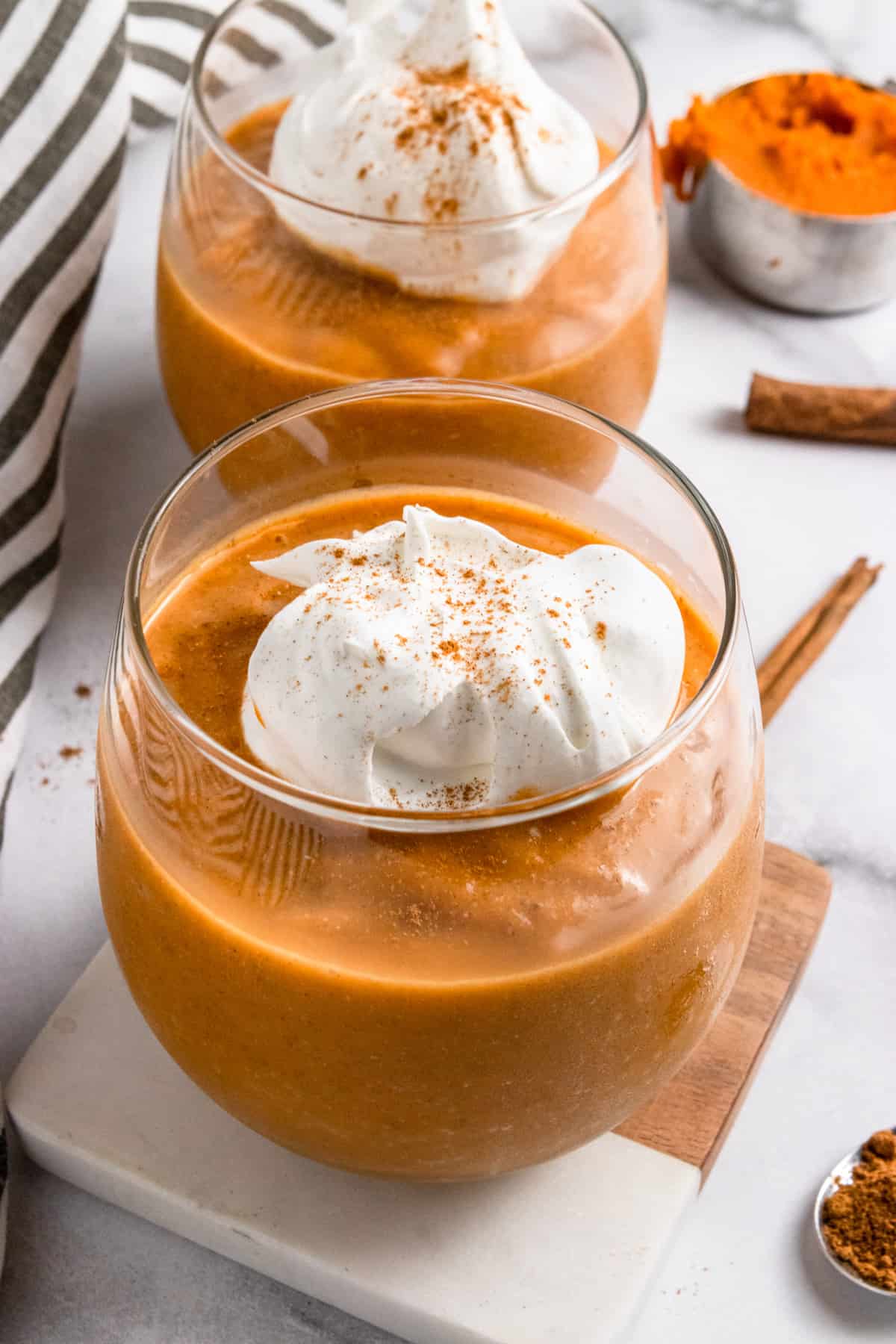 Pumpkin smoothie in glass with whipped cream on top.