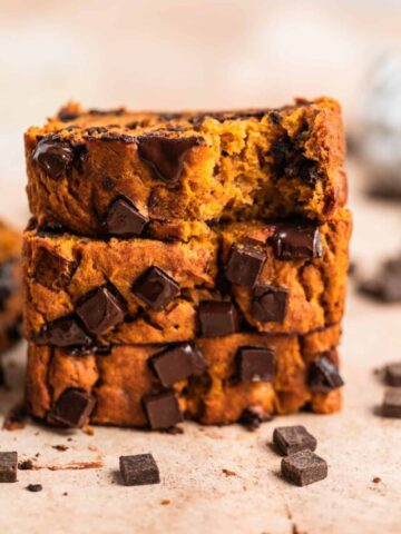 Stack of pumpkin chocolate chip banana bread on surface.
