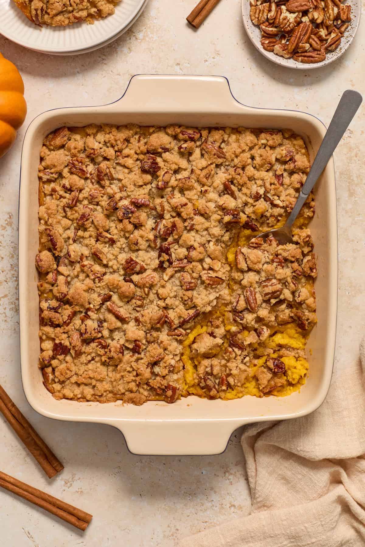 Butternut squash casserole in baking pan with serving spoon scooping into it.