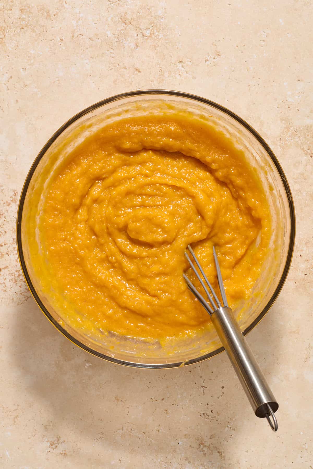 Squash mixture in glass bowl with whisk.