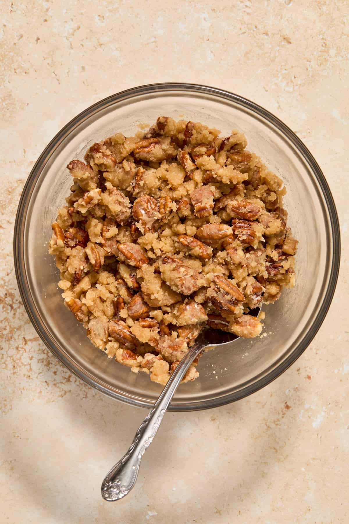 Pecan crumble mixture in mixing bowl with spoon.