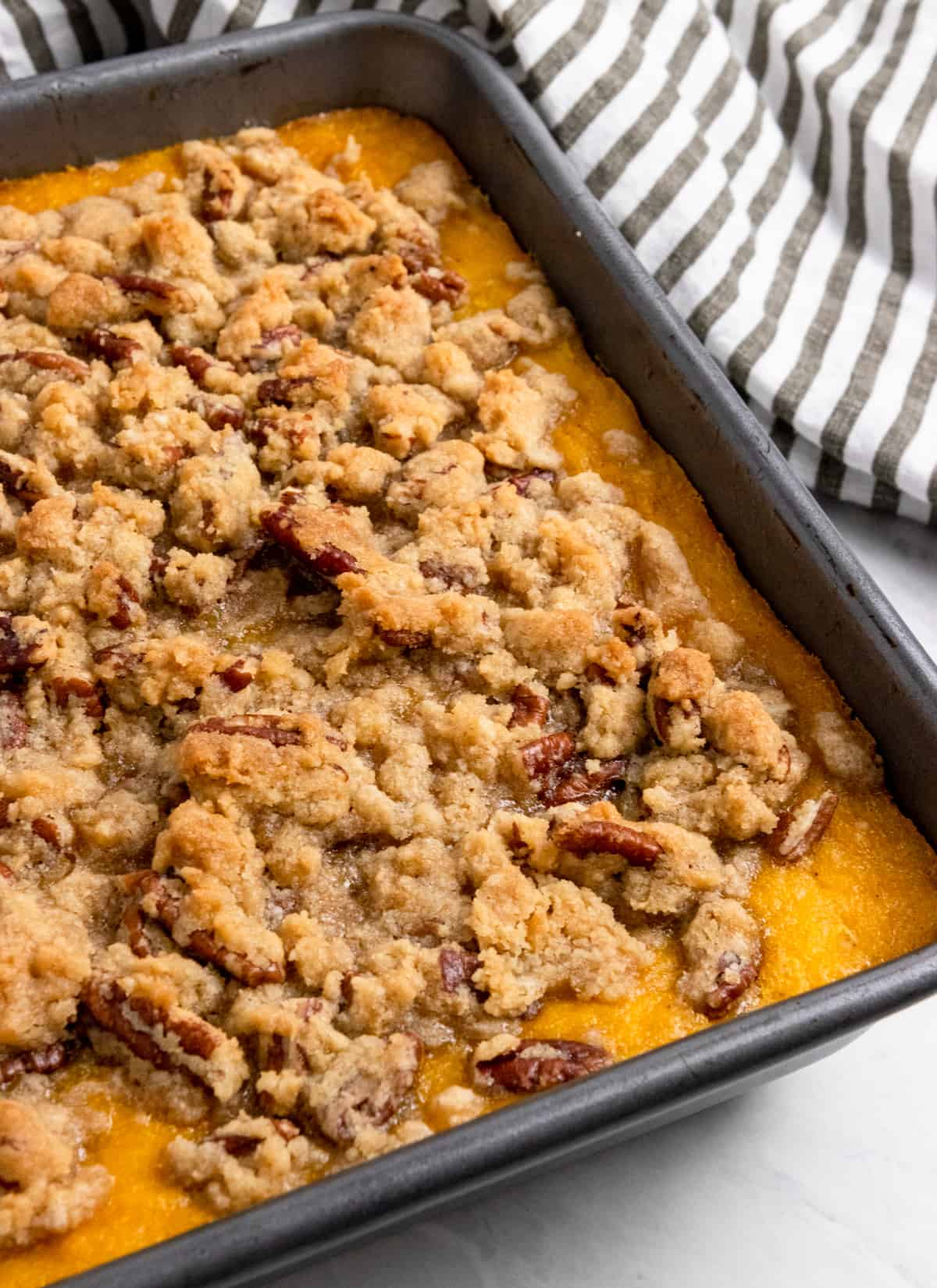 Butternut squash casserole in pan with striped linens.