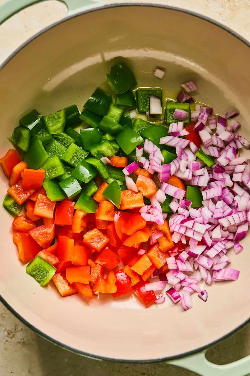 Red onion and bell peppers in dutch oven pot being sautéed. 