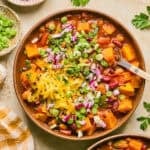 Overhead view of bowl with butternut squash chili with spoon scooping into the bowl.